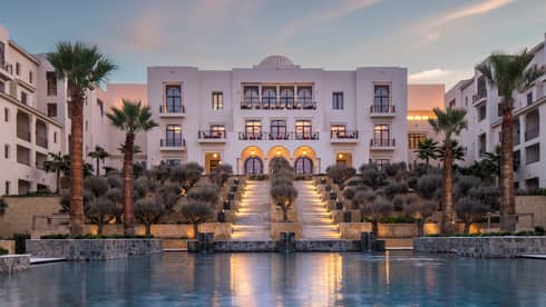Four Seasons Hotel Tunis modern white buildings around pool, palm trees at sunset