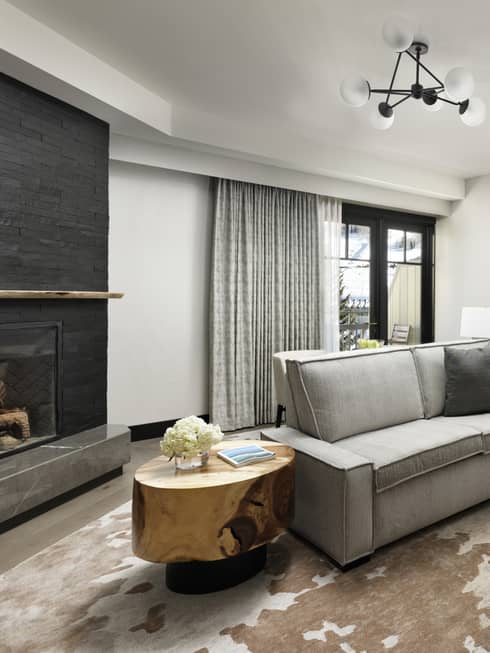 Living room with small grey sofa, arm chair and ottoman, wooden side table