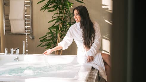Woman sits at side of spa hot tub with spa robe on