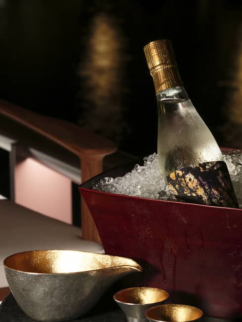 Bottles of sake and Champagne in brown ice bucket on table with glasses