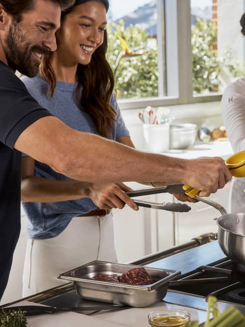 Four guests smiling while cooking in the kitchen.