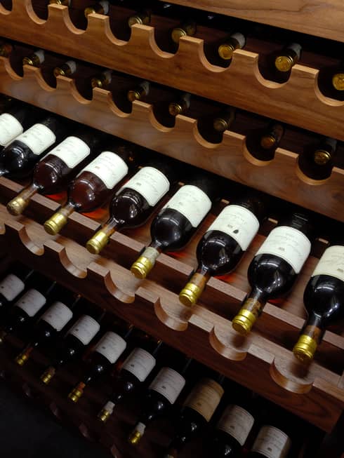 A wine collection arranged on a wooden shelf