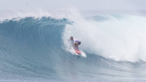 A person rides a wave surfing