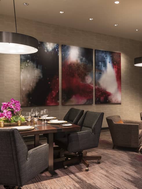 Plush grey dining chairs, art around table, seating area in dimly-lit meeting room
