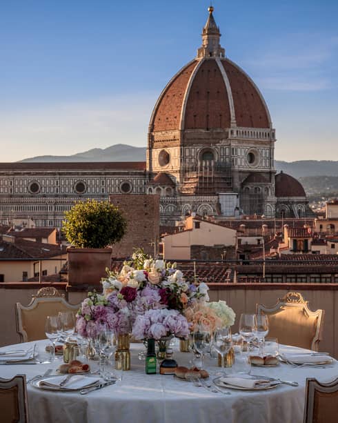 A white linen table set with flowers, and overlooking the historic downtown of Firenze. 