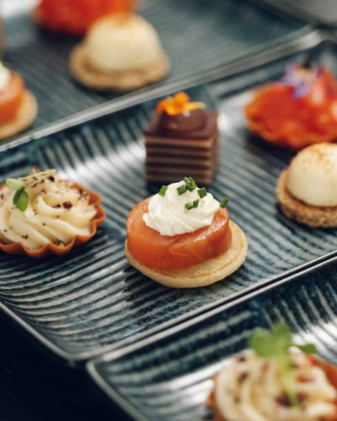 Artistic, dark-glazed rectangular plates hold colourful small bites and hors' doeuvres.