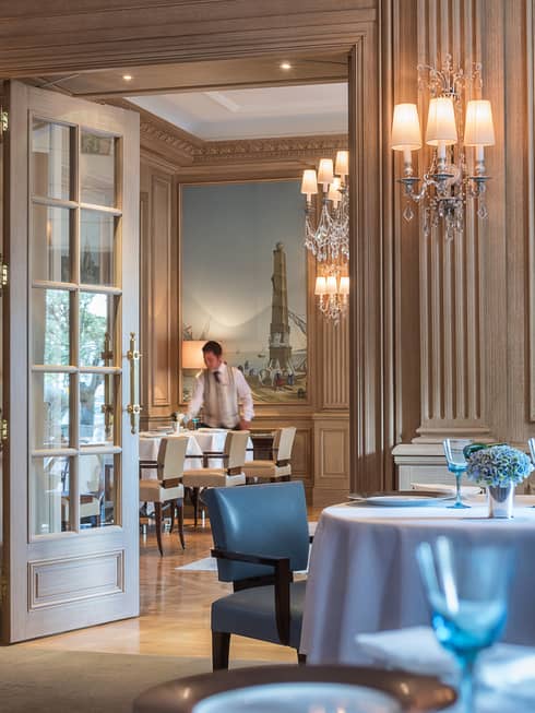 Il Lago dining room with high ceilings, cream walls and bright blue painting, chairs, glassware