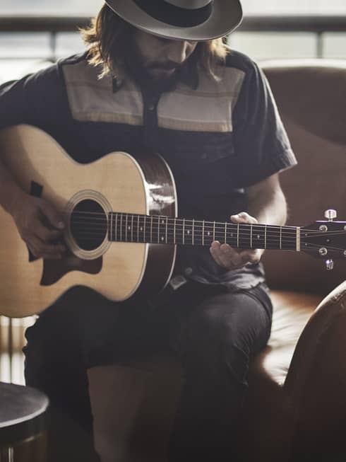 Guitar Concierge plays Taylor acoustic guitar on modern armchair