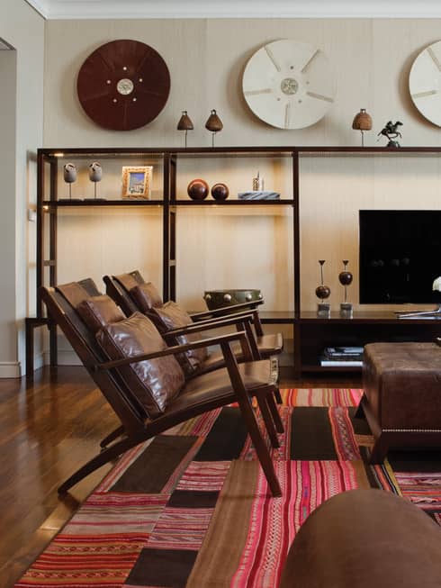 Modern brown leather armchairs and large ottoman with fresh flowers, modern and wood Argentine-inspired art