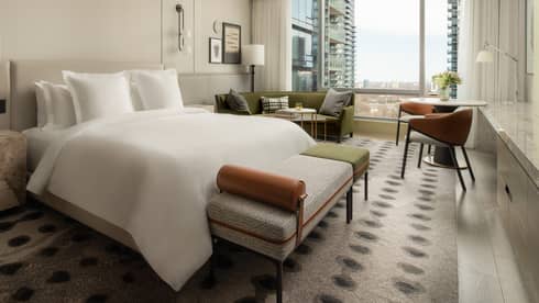Five-star hotel room with a king-size bed, stylish furnishings, and floor-to-ceiling windows overlooking the cityscape