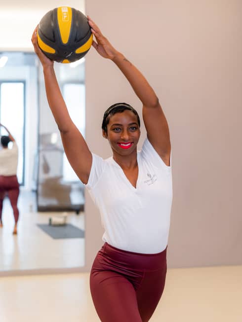 Health expert and personal trainer Mickey Hodges stretches while holding a medicine ball.