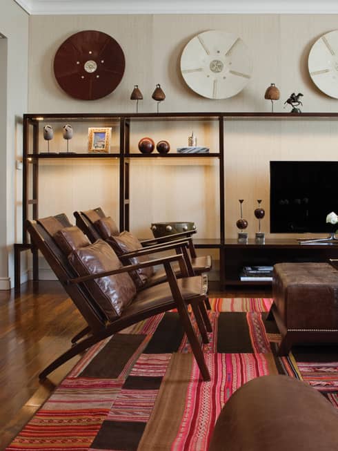 Modern brown leather armchairs and large ottoman with fresh flowers, modern and wood Argentine-inspired art