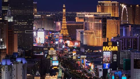 An elevated view of hotels and casinos on the busy night-time Las Vegas strip with the city shining brightly around it.