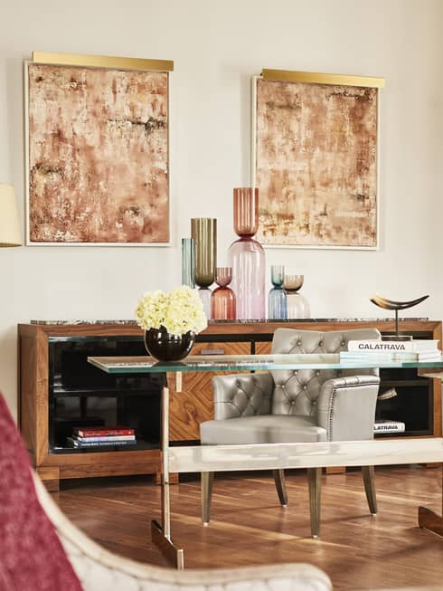 Glass-top desk, leather chair, two paintings hang on white wall