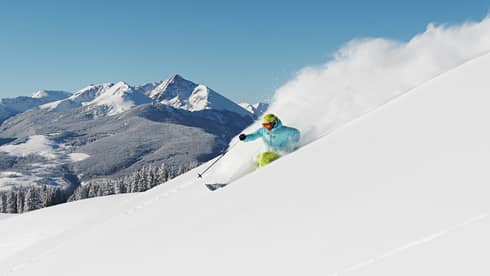 Person skiing down snow covered mountain top