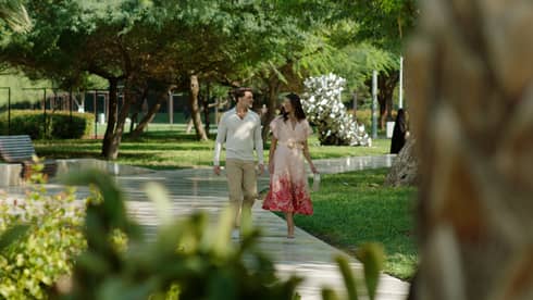 Couple walks along pathway surrounded by flora and fauna