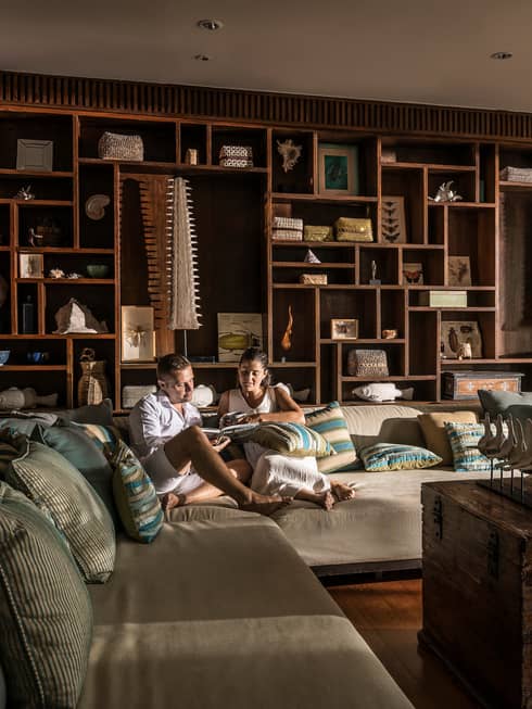 Couple relaxes on oversized plush L-shaped sofa by open door with flowing curtains