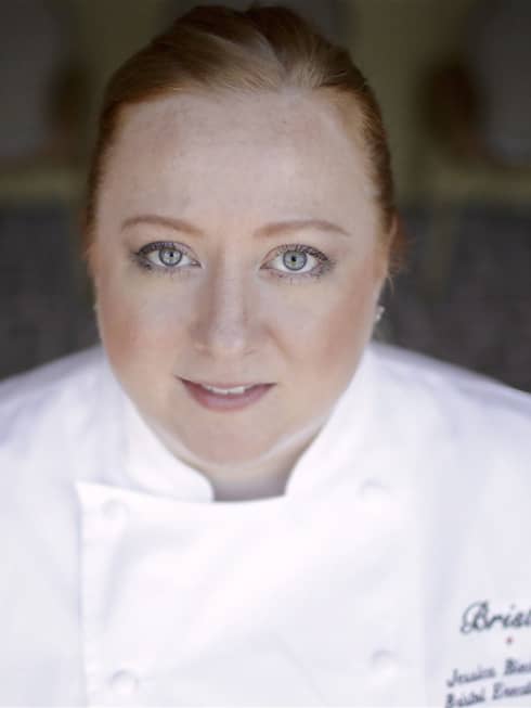 Portrait photo of Executive Chef Jessica Biederman, smiling in white chef's coat