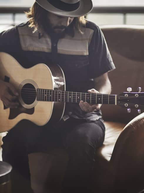 Guitar Concierge plays Taylor acoustic guitar on modern armchair