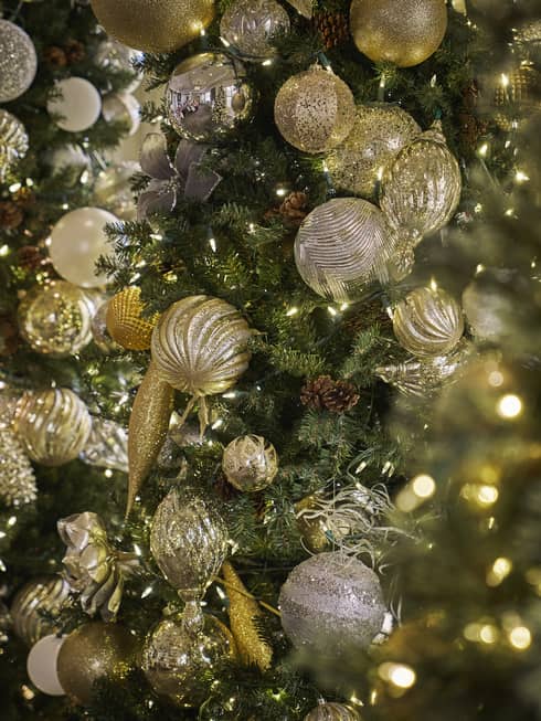 Closeup of Christmas tree with gold ornaments and white string lights