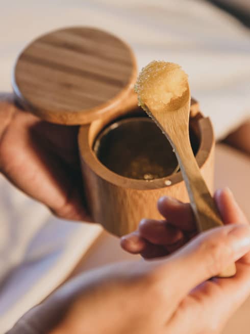 A spa staff member scoops some sugar scrub out of a bamboo container in Hawaii