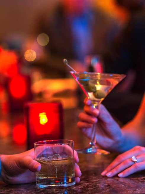 Ty Bar close-up of man and woman holding cocktails in rock and martini glasses, red candle