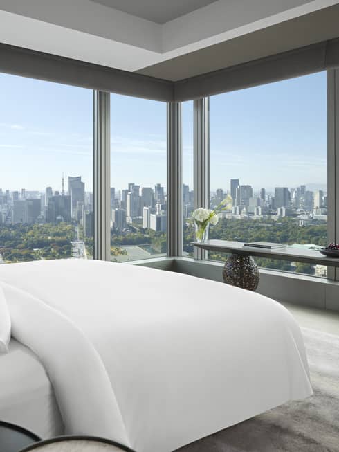 Panoramic hotel room with a king bed, side table with flowers and long console table with orchids