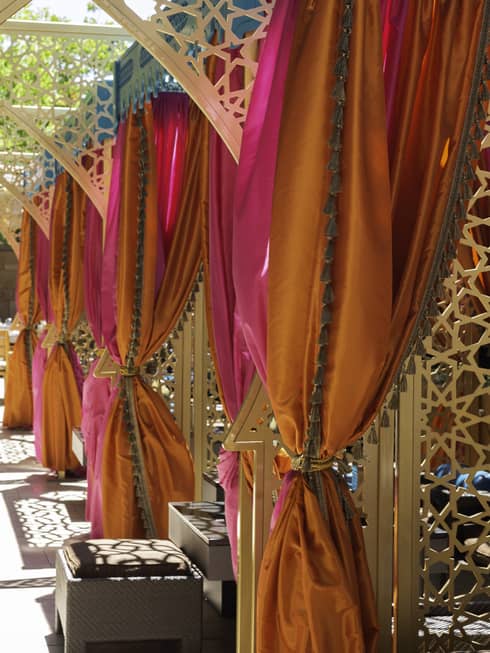 Patio decorated with gold Arabesque-style archways and curtains in pink, orange and blue