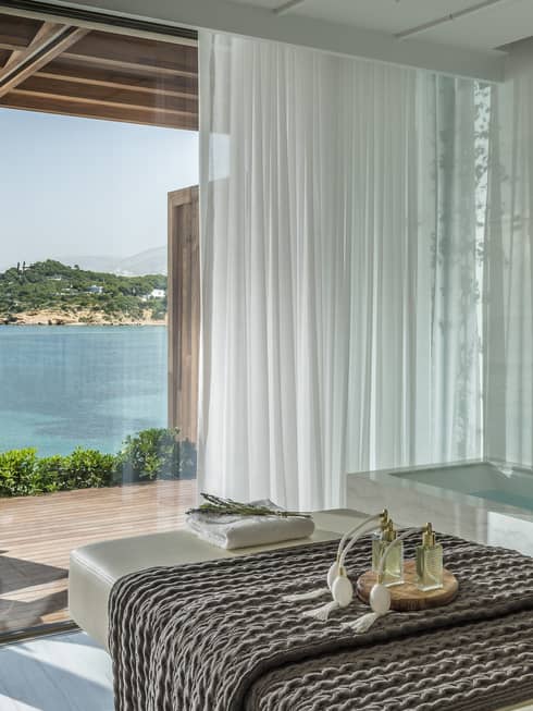 White spa table with dark blanket and water view from tall windows