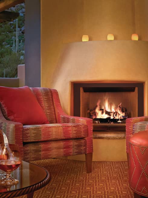 Red-and-brown Southwestern-style patterned armchair, leather footstool in front of gas fireplace