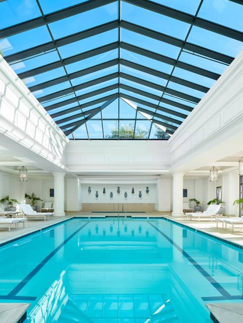 Indoor pool with lounge chairs and ceiling with windows.