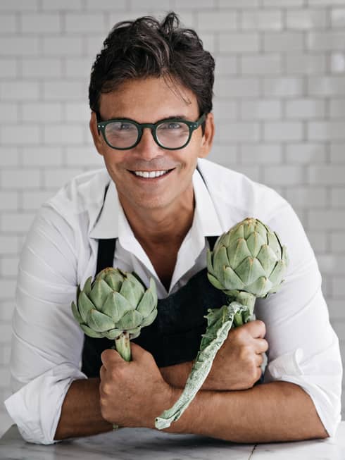 Portrait of Chef Matthew Kenny holding artichokes