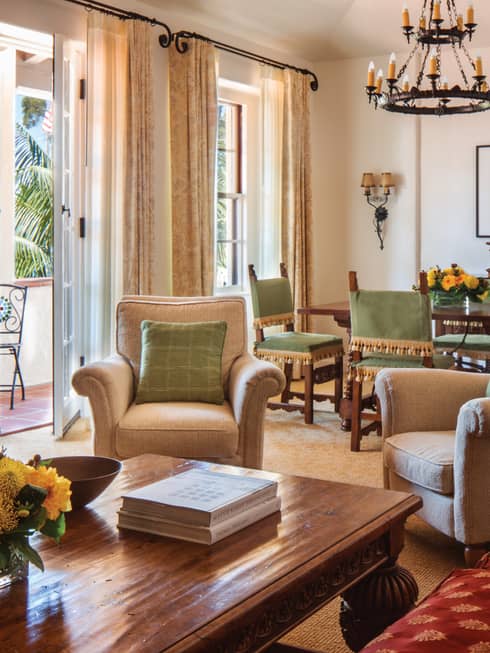 Sunny dining and seating area with open patio door, plush armchairs, wood table