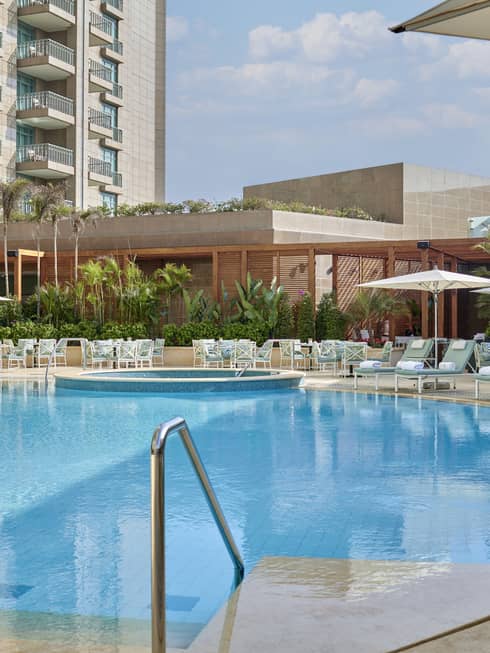 Outdoor pool with lounge chairs lining the edge, umbrellas, foliage