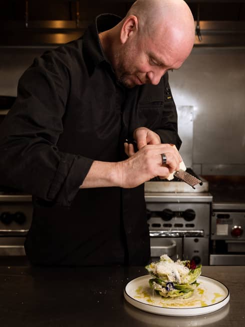 A chef standing in the kitchen and preparing a culinary dish