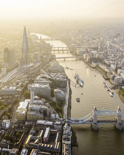 Aerial view of London city buildings along River Thames, London bridge in foreground 