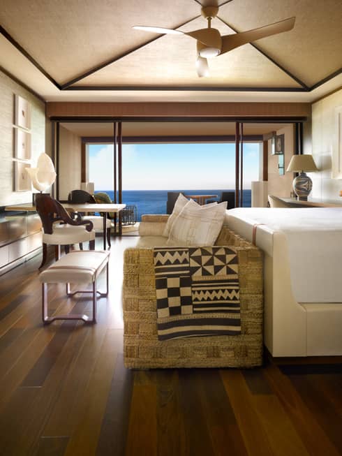 Throw blanket with traditional barkcloth, woodcut-style pattern over wicker sofa at foot of bed