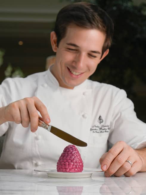 Chef Nicolas Lambert holding small knife, icing berry-shaped dessert