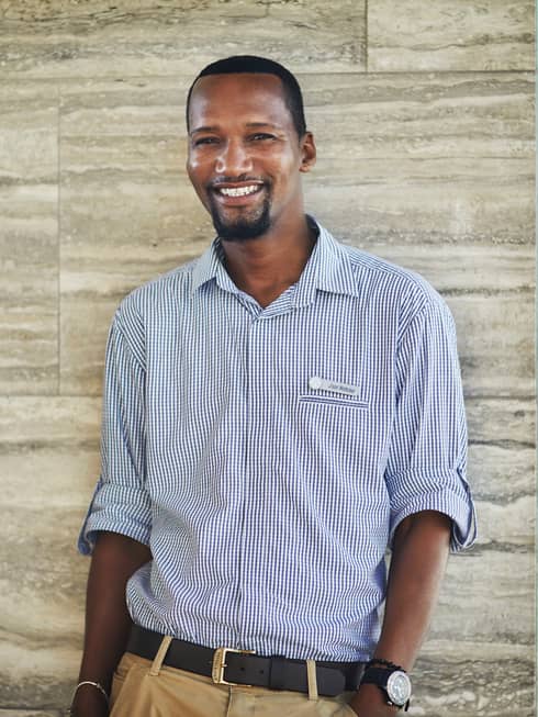 Portrait image of smiling personal assistant standing against marble wall