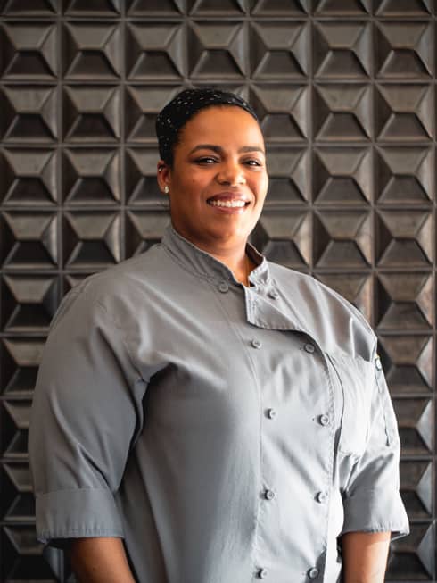 A woman in light grey chef clothes.