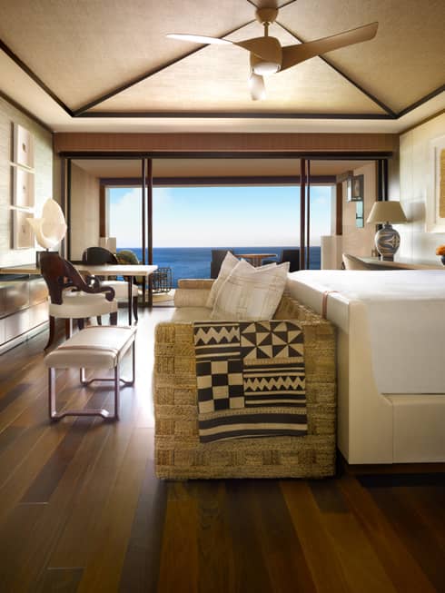 Throw blanket with traditional barkcloth, woodcut-style pattern over wicker sofa at foot of bed