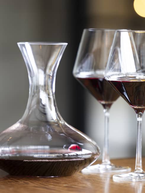 Two wine glasses on a table beside a wine pitcher