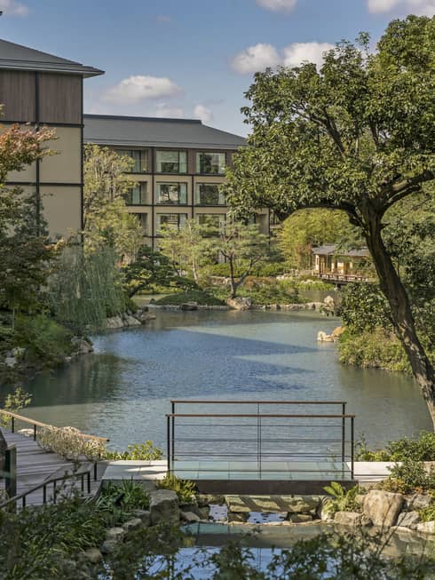 Trees, Shakusuien garden around pond under Four Seasons Hotel Kyoto building