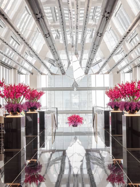 An event room with bouquets of pink flowers and windows along the walls and ceiling