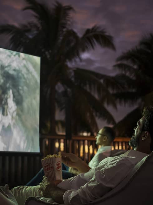 Group of people sit on bean bags with popcorn watching movie under the stars 