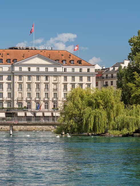Exterior view of Four Seasons Hotel des Bergues historic building on sunny day by lake