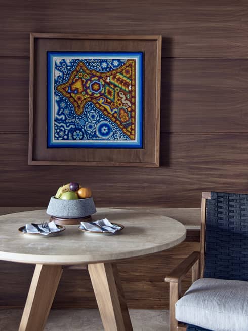 A guest room at Four Seasons Resort in Punta Mita, near Puerto Vallarta, featuring a table with fruit bowl and a locally inspired artwork on the wall