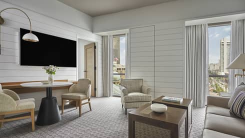 Suite with white panel walls, coffee table, sofa, two chairs, small table and television