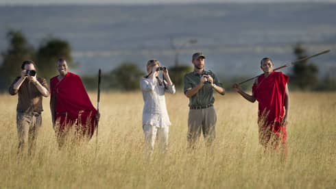 Couple takes photos on walking safari through tall grass with guides