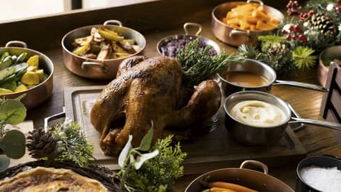 A festive holiday table with turkey, vegetables and other food
